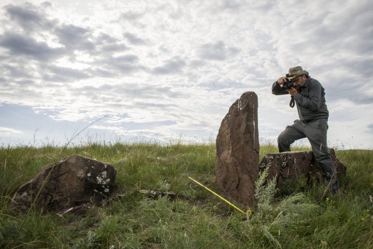 Scientifique photographiant une stèle dans la steppe